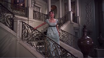 Movie still from “War and Peace” (1956), directed by King Vidor – A woman in a striped dress standing on a staircase; Wide shot, Low angle