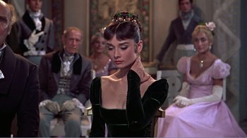 Movie still from “War and Peace” (1956), directed by King Vidor – A woman sitting in front of a group of people; Close Up shot, Over the shoulder angle