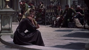 Movie still from “War and Peace” (1956), directed by King Vidor – A woman sitting on the ground in front of a group of people; Wide shot, Low angle