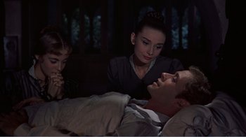 Movie still from “War and Peace” (1956), directed by King Vidor – A man laying in bed next to a woman and a child; Medium shot, High angle