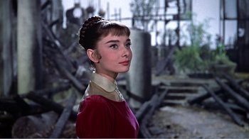 Movie still from “War and Peace” (1956), directed by King Vidor – A woman in a red dress standing in front of a pile of rubble; Close Up shot, Low angle