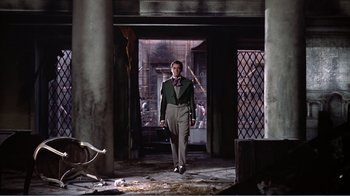 Movie still from “War and Peace” (1956), directed by King Vidor – A man holding a baseball bat while standing in an abandoned building; Wide shot, Low angle