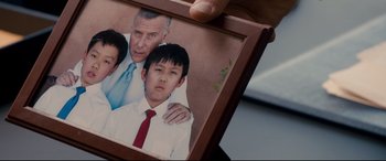 Movie still from “War on Everyone” (2016), directed by John Michael McDonagh – A person holding a picture frame with a picture of a man and a boy; Close Up shot, High angle
