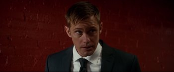 Movie still from “War on Everyone” (2016), directed by John Michael McDonagh – A person wearing a suit and tie; Close Up shot, Over the shoulder angle