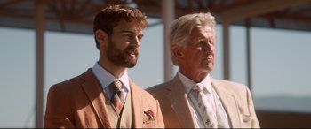 Movie still from “War on Everyone” (2016), directed by John Michael McDonagh – A man and a man in a suit and tie standing next to each other; Medium shot, Low angle