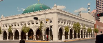 Movie still from “War on Everyone” (2016), directed by John Michael McDonagh – People are walking on the sidewalk in front of a building; Extreme Wide shot, Low angle