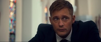 Movie still from “War on Everyone” (2016), directed by John Michael McDonagh – A person wearing a suit and tie; Close Up shot, Over the shoulder angle
