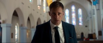 Movie still from “War on Everyone” (2016), directed by John Michael McDonagh – A person wearing a suit and tie; Close Up shot, Low angle