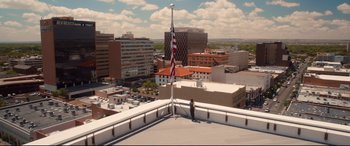 Movie still from “War on Everyone” (2016), directed by John Michael McDonagh – A person standing on a roof top with a flag; Extreme Wide shot, Low angle
