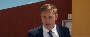 Movie still from “War on Everyone” (2016), directed by John Michael McDonagh – A person wearing a suit and tie; Close Up shot, Over the shoulder angle