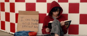 Movie still from “War on Everyone” (2016), directed by John Michael McDonagh – A young man sitting on the ground reading a book; Medium shot, High angle