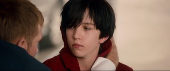 Movie still from “War on Everyone” (2016), directed by John Michael McDonagh – A young boy with long black hair wearing a red and white jacket; Close Up shot, Over the shoulder angle