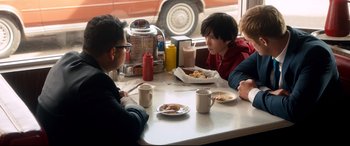 Movie still from “War on Everyone” (2016), directed by John Michael McDonagh – A group of people sitting at a table eating food; Medium shot, Over the shoulder angle