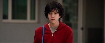 Movie still from “War on Everyone” (2016), directed by John Michael McDonagh – A young man in a red jacket with a blue bag; Close Up shot, Low angle