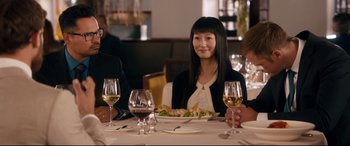 Movie still from “War on Everyone” (2016), directed by John Michael McDonagh – A woman sitting at a table with a plate of food; Medium shot, Over the shoulder angle