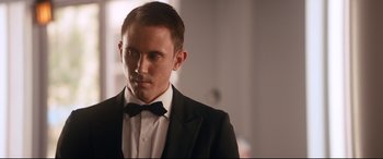 Movie still from “War on Everyone” (2016), directed by John Michael McDonagh – A person wearing a suit and a bow tie; Close Up shot, Over the shoulder angle
