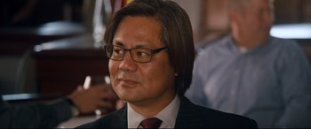 Movie still from “War on Everyone” (2016), directed by John Michael McDonagh – A person wearing a suit and tie; Close Up shot, Over the shoulder angle