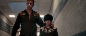 Movie still from “War on Everyone” (2016), directed by John Michael McDonagh – A man and a boy are walking down a hall way; Medium shot, Low angle