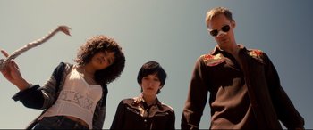 Movie still from “War on Everyone” (2016), directed by John Michael McDonagh – A group of people standing next to each other under a blue sky; Medium shot, Low angle