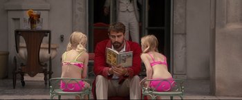 Movie still from “War on Everyone” (2016), directed by John Michael McDonagh – A man reading a book to two little girls; Medium shot, Over the shoulder angle