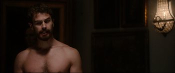 Movie still from “War on Everyone” (2016), directed by John Michael McDonagh – A man with no shirt is standing in a room; Medium shot, Over the shoulder angle