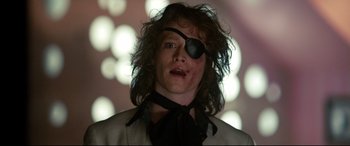 Movie still from “War on Everyone” (2016), directed by John Michael McDonagh – A man wearing a pirate eye patch and a suit; Close Up shot, Low angle