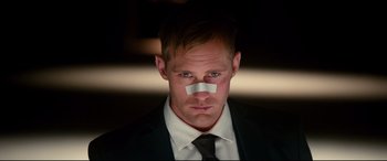 Movie still from “War on Everyone” (2016), directed by John Michael McDonagh – A person wearing a suit with a piece of paper on his face; Close Up shot, Low angle