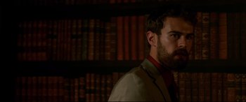 Movie still from “War on Everyone” (2016), directed by John Michael McDonagh – A man standing in front of a book shelf; Close Up shot, Low angle