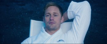 Movie still from “War on Everyone” (2016), directed by John Michael McDonagh – A man in a white bathrobe laying on his stomach; Close Up shot, High angle