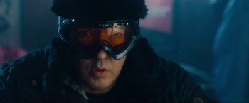 Movie still from “War, Inc.” (2008), directed by Joshua Seftel – A man wearing goggles and wearing a hat; Close Up shot, Over the shoulder angle