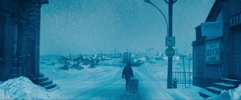 Movie still from “War, Inc.” (2008), directed by Joshua Seftel – A man riding a bike down a snow covered street; Extreme Wide shot, High angle