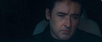 Movie still from “War, Inc.” (2008), directed by Joshua Seftel – A man's face in the dark; Close Up shot, Low angle