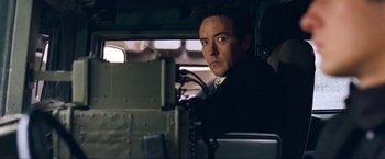 Movie still from “War, Inc.” (2008), directed by Joshua Seftel – A man sitting in a vehicle looking at the camera; Close Up shot, Low angle