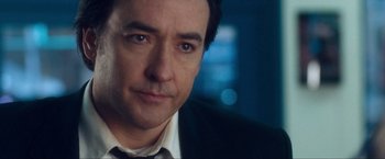 Movie still from “War, Inc.” (2008), directed by Joshua Seftel – A person wearing a suit and tie; Close Up shot, Over the shoulder angle