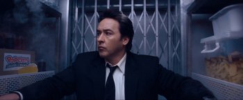 Movie still from “War, Inc.” (2008), directed by Joshua Seftel – A person wearing a suit and tie; Close Up shot, Low angle