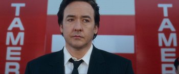 Movie still from “War, Inc.” (2008), directed by Joshua Seftel – A person wearing a suit and tie; Close Up shot, Low angle