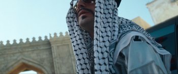 Movie still from “War, Inc.” (2008), directed by Joshua Seftel – A person wearing a hat and a scarf; Close Up shot, Low angle
