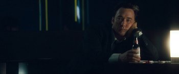 Movie still from “War, Inc.” (2008), directed by Joshua Seftel – A man in a suit and tie sitting in front of a window; Close Up shot, Low angle