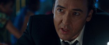 Movie still from “War, Inc.” (2008), directed by Joshua Seftel – A person wearing a suit and tie; Close Up shot, Over the shoulder angle