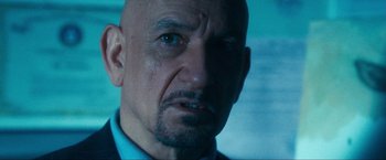 Movie still from “War, Inc.” (2008), directed by Joshua Seftel – A man with a bald head is looking at the camera; Close Up shot, Over the shoulder angle