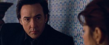 Movie still from “War, Inc.” (2008), directed by Joshua Seftel – A person wearing a suit and tie; Close Up shot, Low angle