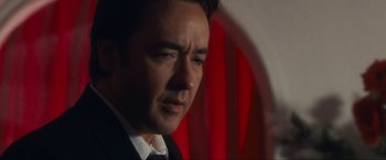 Movie still from “War, Inc.” (2008), directed by Joshua Seftel – A person wearing a suit and tie; Close Up shot, Over the shoulder angle