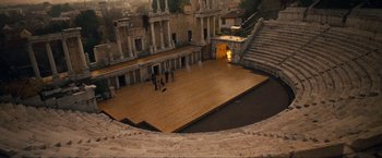 Movie still from “War, Inc.” (2008), directed by Joshua Seftel – An outdoor stage with people standing on it; Extreme Wide shot, High angle