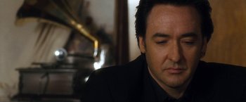 Movie still from “War, Inc.” (2008), directed by Joshua Seftel – A person wearing a suit and tie; Close Up shot, Low angle