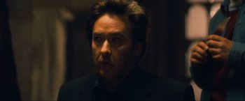 Movie still from “War, Inc.” (2008), directed by Joshua Seftel – A person wearing a suit and tie; Close Up shot, Low angle