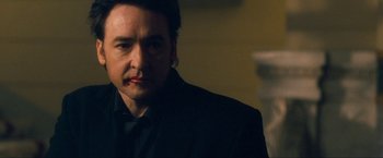 Movie still from “War, Inc.” (2008), directed by Joshua Seftel – A person wearing a suit; Close Up shot, Over the shoulder angle