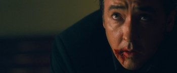 Movie still from “War, Inc.” (2008), directed by Joshua Seftel – A person with blood on his face; Extreme Close Up shot, Low angle