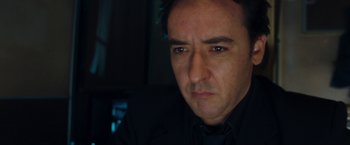 Movie still from “War, Inc.” (2008), directed by Joshua Seftel – A person wearing a suit and tie; Close Up shot, Low angle