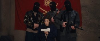 Movie still from “War, Inc.” (2008), directed by Joshua Seftel – A group of people wearing masks and holding guns; Medium shot, Low angle