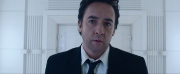 Movie still from “War, Inc.” (2008), directed by Joshua Seftel – A person wearing a suit and tie; Close Up shot, Low angle